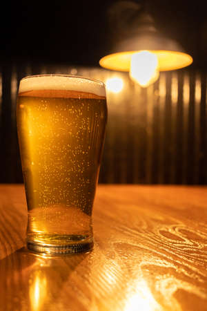 Glass cup served with IPA beer and a bottle and a can at the bottom