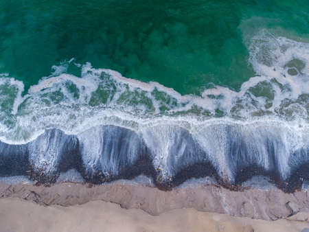 Aerial view of turquoise waves reaching the shore