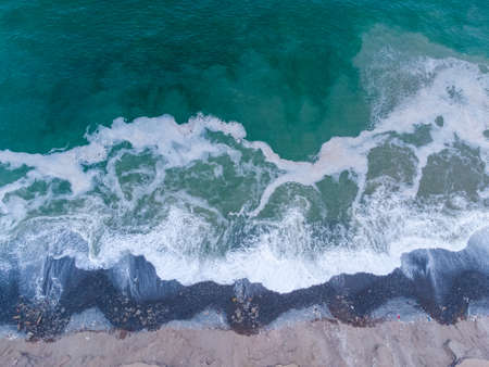 Aerial view of turquoise waves reaching the shore