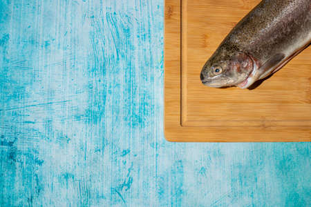 Two fresh fish on kitchen board with blue backgroundの写真素材
