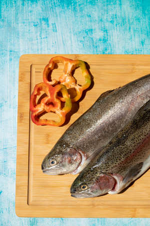 Two fresh fish on kitchen board with blue background