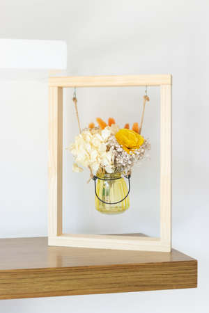 Dried flowers in glass container within a frame as a decoration motifの写真素材