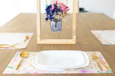 Plate with utensils, on the table decorated with a small flower arrangementの写真素材
