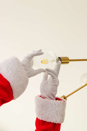 Santa Claus is changing a light bulbの写真素材