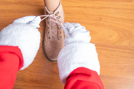 Santa Claus is helping a girl tie her shoelacesの写真素材