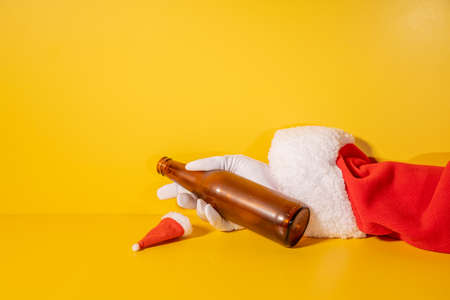 Santa Claus holding beer bottle with his hands on yellow backgroundの写真素材
