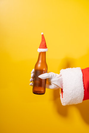 Santa Claus holding beer bottle with his hands on yellow backgroundの写真素材