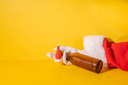 Santa Claus holding beer bottle with his hands on yellow backgroundの写真素材