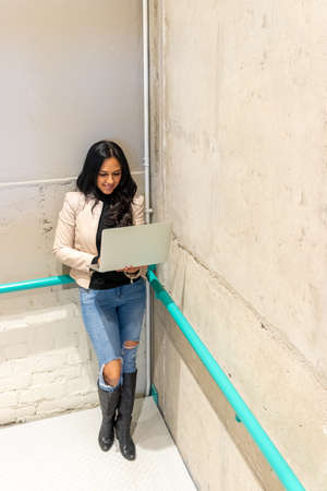 Beauty brunette woman is working with her laptop from the stairsの写真素材