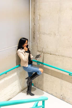 Brunette woman is working with her laptop from the stairsの写真素材