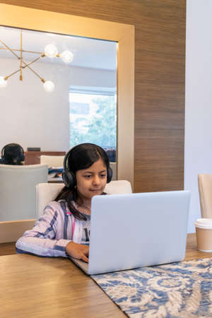 Teenage girl working with her laptop in her living roomの写真素材