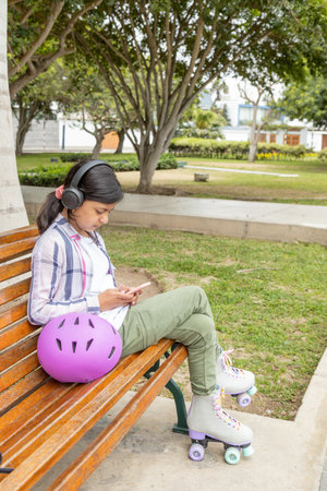 Young teen girl enjoys music while rollerblading in the parkの写真素材