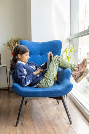 Young girl is using her laptop on the living room sofaの写真素材