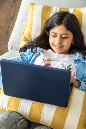 Young teenage girl is using a laptop on the sofaの写真素材