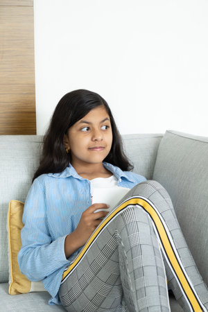 Young teenage girl is reading a book on the sofaの写真素材