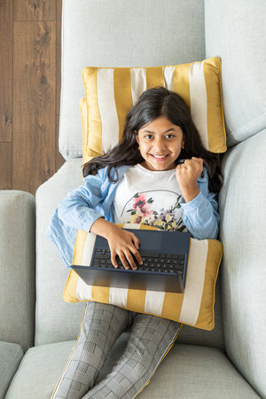 Young teenage girl is using a laptop on the sofaの写真素材