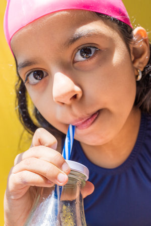 Cute little girl in a swimsuit sunbathing, while having a lemonadeの写真素材