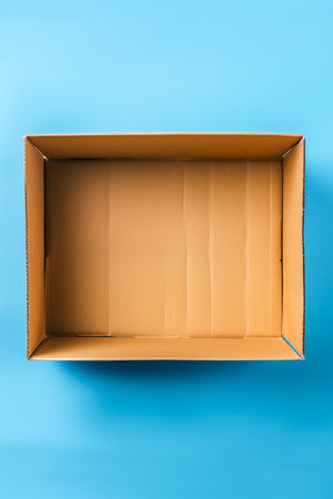 A cardboard box is empty and sits on a blue background. The box is brown and has no contentsの素材