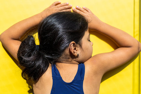 Little girl with a swimsuit is receiving the sun with direct light.