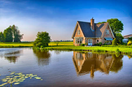 Red bricks house in countryside near the lake with mirror reflection in water, Amsterdam, Holland, Netherlands, HDR Red bricks house in countryside near the lake with mirror reflection in water, Amsterdam, Holland, Netherlands, HDR