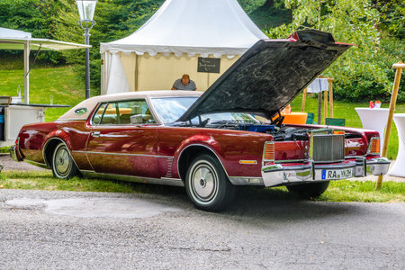 BADEN BADEN, GERMANY - JULY 2019: red maroon LINCOLN CONTINENTAL MARK IV full-size cabrio car 1972 1976 with opened hood, oldtimer meeting in Kurpark.のeditorial素材