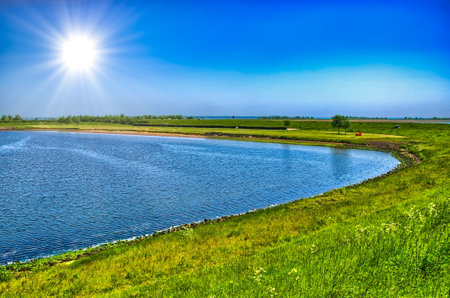 Lake shore with green grass on sunny day, Holland, Netherlands, HDR