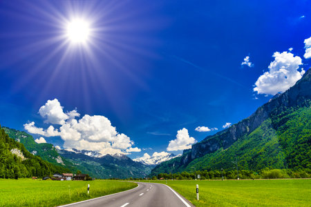 Asphalt road among green meadows, Brienz, Interlaken-Oberhasli, Bern Switzerlandの写真素材