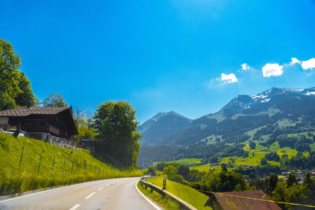 Road among cottages houses and mountains covered with forest in the village Darstetten in Frutigen-Niedersimmental, Bern, Switzerland.の写真素材