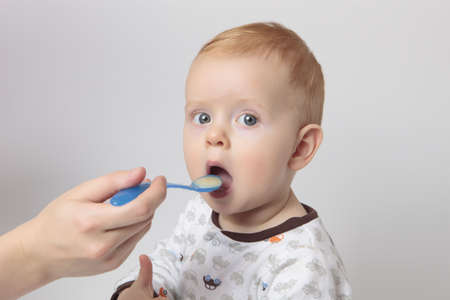 a photo of hungry baby boy and a hand with spoon の写真素材