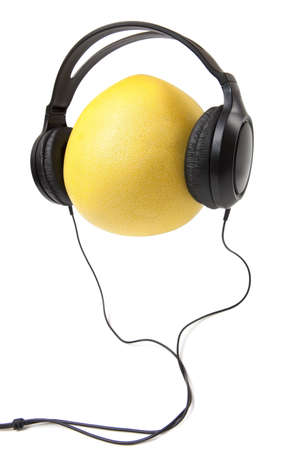 yellow pomelo and black headphones over white の写真素材