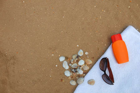 a photo of sunglasses and sunblock on beachtowelの写真素材