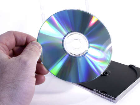 Hand holds CD with case in background.