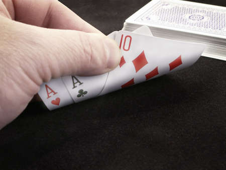 Close-up of hand of cards peeking at two aces and a ten.のeditorial素材