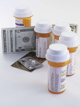 Pill bottles, tablets, with dollars and credit card illustrate the cost of healthcare.の写真素材