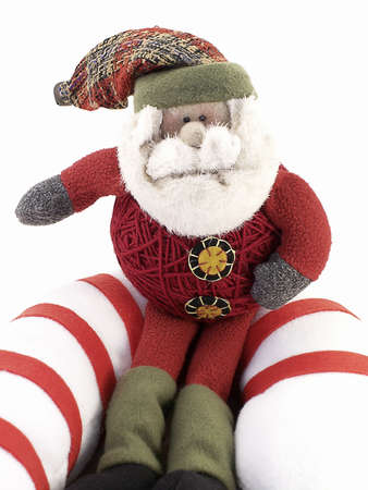 Crafted Santa sits on giant candy-cane, with white background.の写真素材