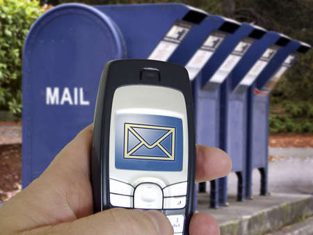 New technology email from cell phone contrasts with a bank of old mail boxes in background.の写真素材