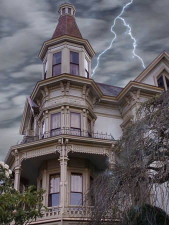 Stern looking victorian mansion weathers a lightening storm in this haunted feeling scene