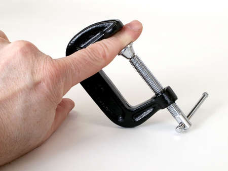 C-Clamp is screwed tight on man's index finger, isolated on white background.の写真素材