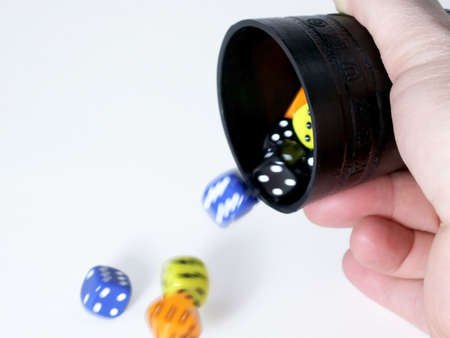 Colorful dice thrown from black cup tumble onto table, isolated on white background.の写真素材