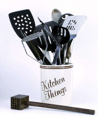 Jar of "Kitchen Things" with spatulas, wooden spoons, and other implements including wooden meat tenderizer in front, isolated on white backgroundの写真素材