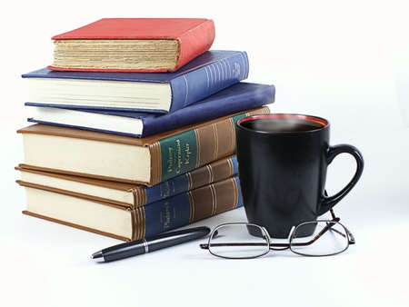 Stack of leather and hardback books with steaming coffee in mug, pen and glasses... ready to study.の写真素材