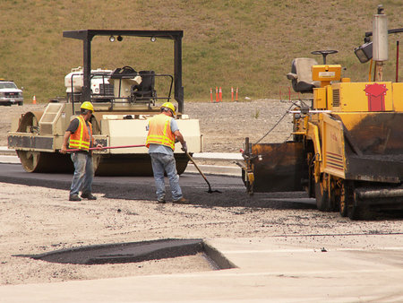 Road paving workers laying asphault with steam rollers at construction site.の写真素材