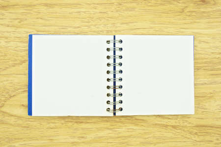 Old blue notebook spread with rusty wire and dirt on paper place on wood background 