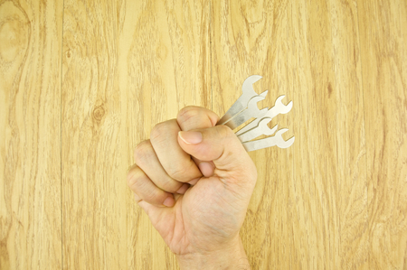 Man holding wrench use for minor repair on wood background.の写真素材