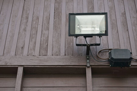 Black spotlight and box on side of brown wall wood.