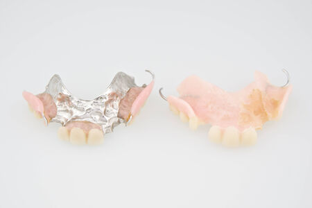Denture made from plastic and metal put on white background.