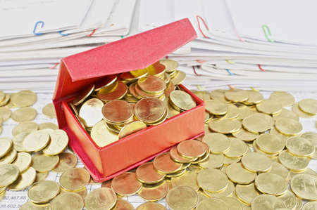Gold coins overload from red box pile of paperwork as background.の写真素材