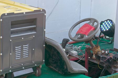 Yellow gasoline generator is  power for old and rust car.