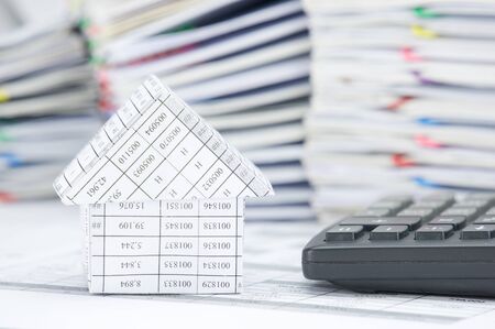 House and calculator on finance account have blur pile of paperwork as background.の写真素材