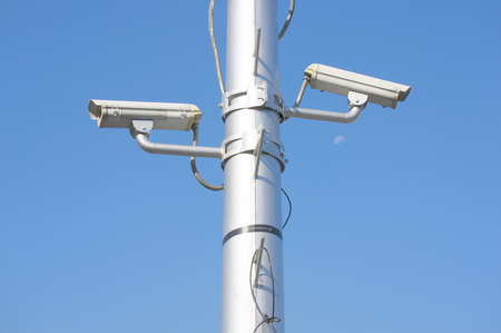 Security camera on high pole at super highway with blue sky.